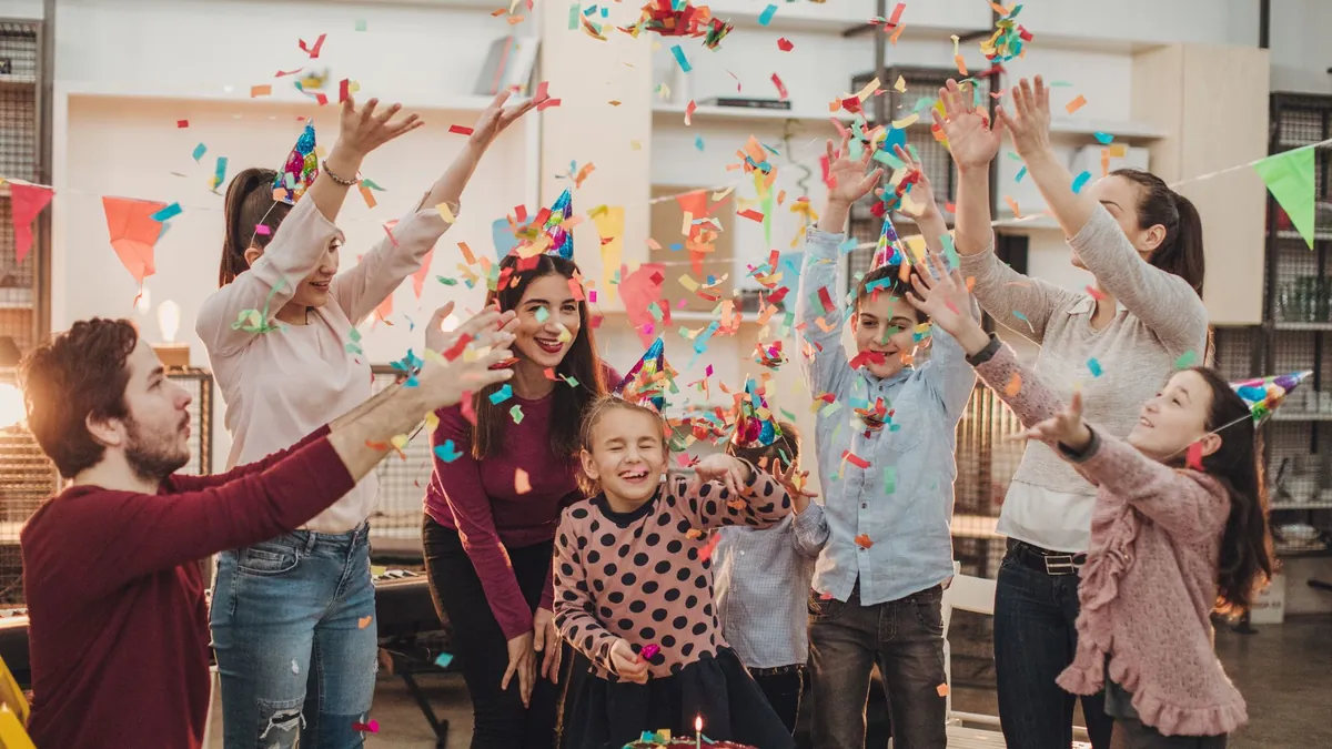 A child smiling brightly while being the centre of a birthday party